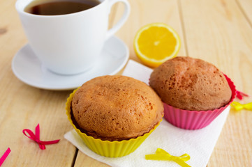 Light lemon cupcakes muffins on wooden background and a cup of tea.