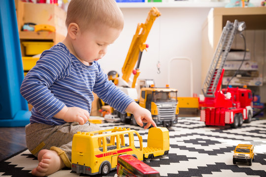 Cute little baby boy playing with toy school bus in his room. Indoors activities with children. Child playing in kid's room.