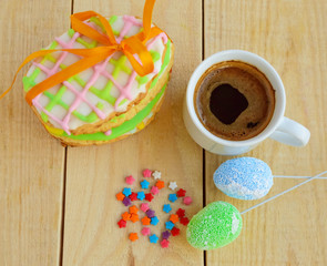 Holiday Gingerbread Cookie in the form of an egg, with multicolored glaze on a blue napkin and cup of coffee.