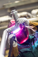 Industrial worker with protective mask welding inox elements in steel structures manufacture...