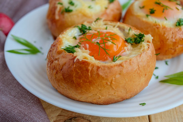 Eggs baked in a bun with ham, cheese and herbs. French breakfast.