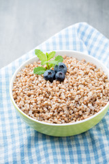 Buckwheat porridge in a bowl with mint leaves and blueberries.