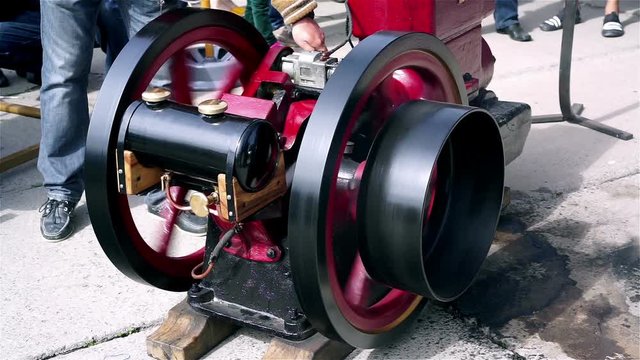 Engineer starting vintage diesel engine, flywheels rotating, retro technologies
