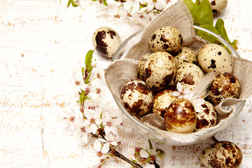 Spring easter composition with eggs in a glass plate with a linen cloth and cherry flowers on a white  old wooden background