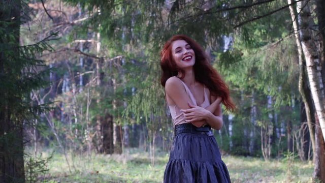 Pretty girl in skirt laughs in sunny autumn forest