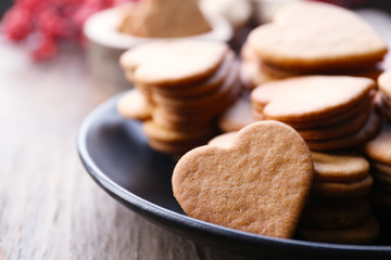 Heart shaped biscuits on plate with ash berry on wooden background