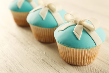 Tasty cupcakes with bow on light background