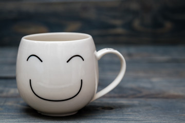 White Cup with Smiley Face on Blue Wooden Table