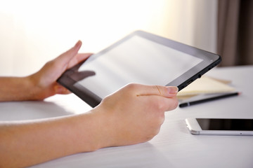 Mobile phone and female hands using modern tablet, indoors