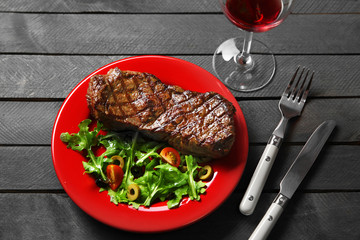 Grilled steak with vegetable salad and glass of wine, closeup