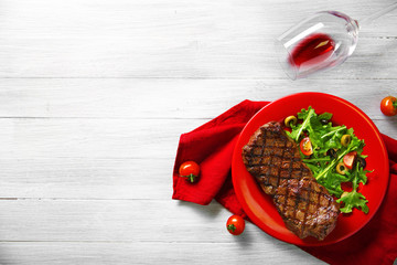 Grilled steak with vegetable salad and wine, closeup