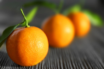 Fresh tangerines with leaves on wooden table, closeup