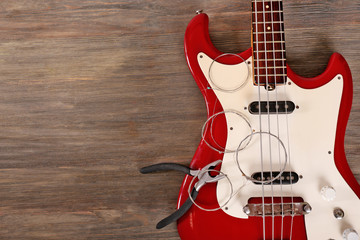 Electric guitar with pliers and strings on wooden background