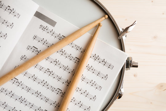 Music score drumsticks and drum tuner over a snare drum