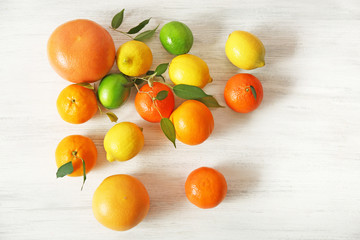 Fresh citrus fruits with green leaves on wooden background