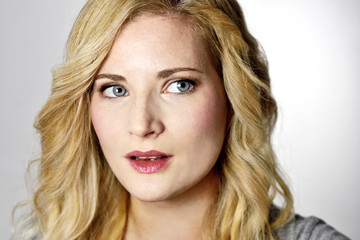 Fototapeta premium Beautiful blond woman looking to the side. Positive Emotions. Young woman on grey background.