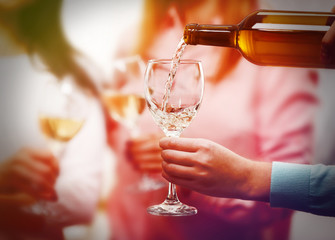 Pouring white wine into glass at hen-party, close up