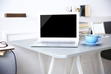 Modern interior. Comfortable workplace. Table with laptop and cup of coffee on it