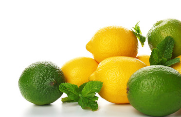 A heap of lemons and limes with mint sprigs isolated on a white background, close up