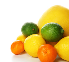 A heap of mixed citrus fruit including   lemons, limes, tangerines and pomelo isolated on a white background, close up