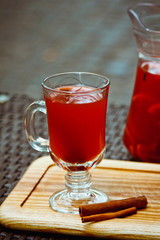 Refreshing summer fruit lemonade with orange and cinnamon in a beautiful glass and jar on wooden background