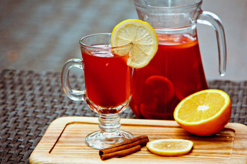 Refreshing summer fruit lemonade with orange and cinnamon in a beautiful glass and jar on wooden background