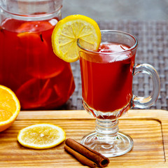 Refreshing summer fruit lemonade with orange and cinnamon in a beautiful glass and jar on wooden background