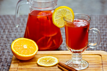 Refreshing summer fruit lemonade with orange and cinnamon in a beautiful glass and jar on wooden background