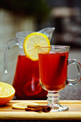 Refreshing summer fruit lemonade with orange and cinnamon in a beautiful glass and jar on wooden background