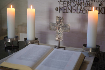 Altarraum mit Bibel, Kreuz und brennenden Kerzen, andächtige, sakrale Szene, warmes Kerzenlicht