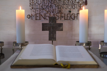 Altarraum mit Bibel, Kreuz und brennenden Kerzen, sakrale, andächtige Stimmung, warmes...