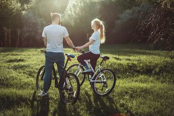 Beautiful young couple in love walking with bicycles hugging and looking at each other. The concept of joy and happiness