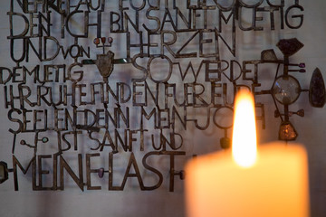 warmes Kerzenlicht in Altarraum mit Bibel, Kreuz und brennender Kerze und Kunst