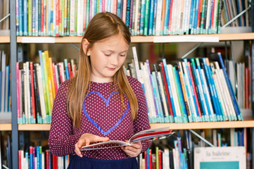 Little girl reading book in the library