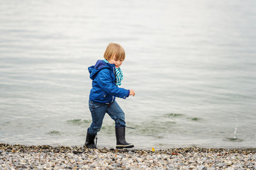 Little boy playing by the lake on a cloudy day