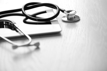 Stethoscope and tablet on wooden background