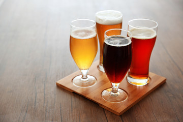 Glasses with different sorts of craft beer on wooden tray