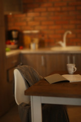 Modern table with cup and book in the kitchen
