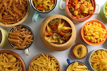 Various types of pasta in dishes, top view