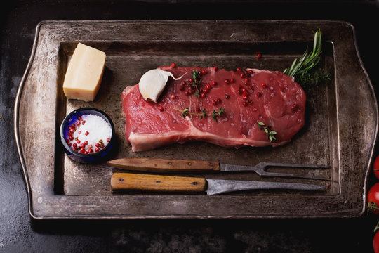 Raw striploin beef steak on black background