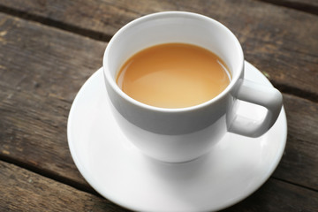 Cup of tea with milk on wooden background