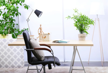 Workplace with table, office chair and lamp in living room