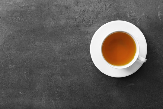 Cup of tea on grey background, top view