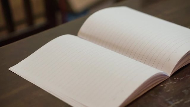 blur, blowing pages of white blank notebook on table 