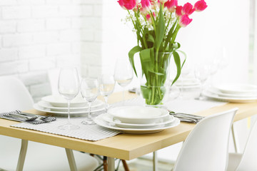 Table served with white dishes and a bouquet of tulips