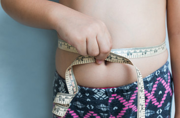 girl measuring her waistline with measure tape