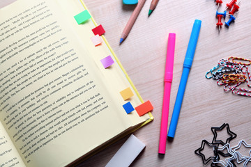 Open book with bookmarks on wooden table