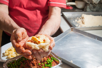 The making of sicilian arancini: cook modelling a rice arancino filled with italian ragu in a typical cone shape