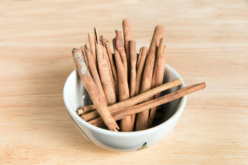 bowl of cinnamon stick on a wood background