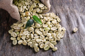 Green coffee beans with a leaf on  wooden table